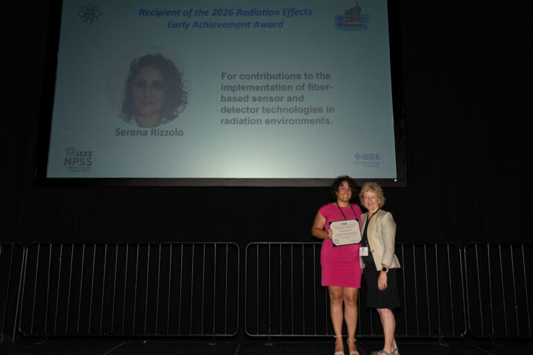 Serena Rizzolo receiving the 2026 Radiation Effects Early Achievement Award from Kay Chesnut at NSREC 2026 in San Juan
